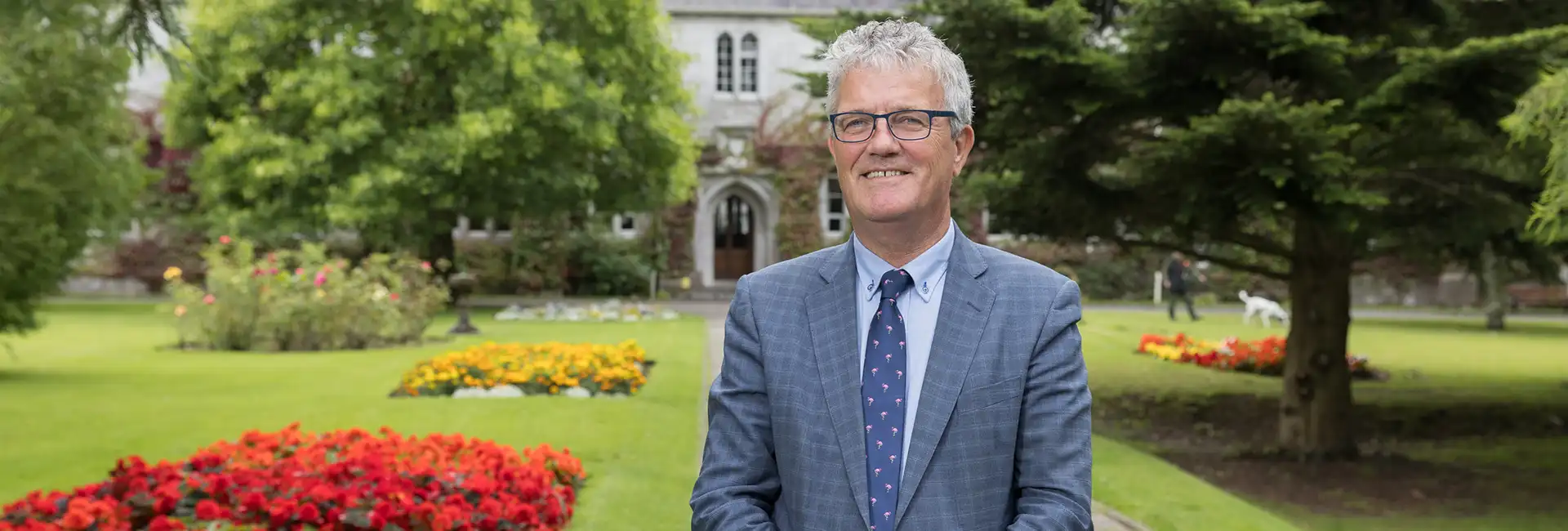 Image of UCC President John OHalloran standing in the Presidents Garden on a sunny day