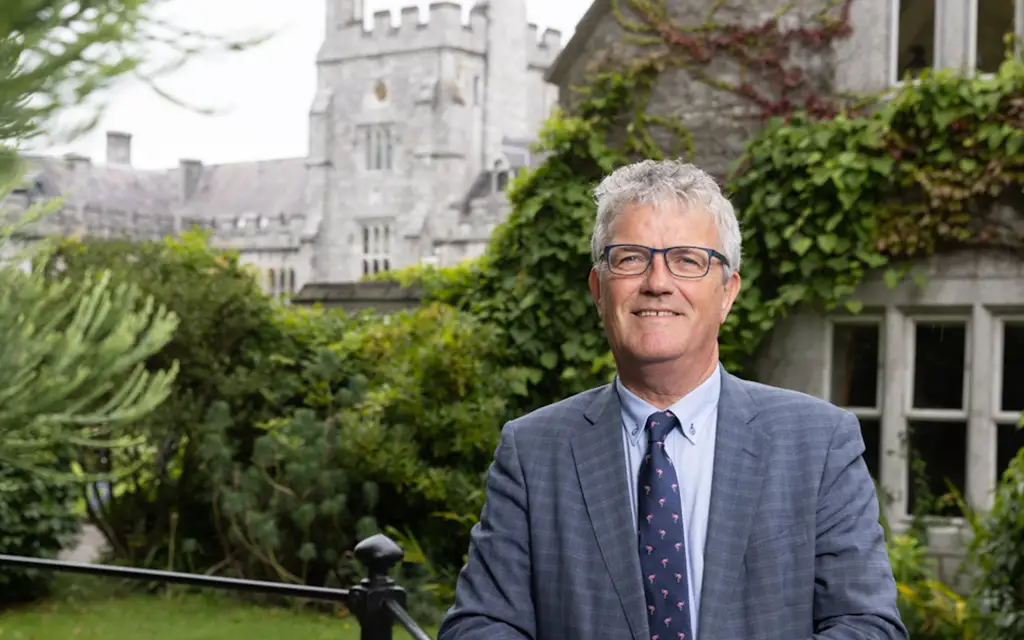 President Professor John O'Halloran standing in front of UCC's main quadrangle building