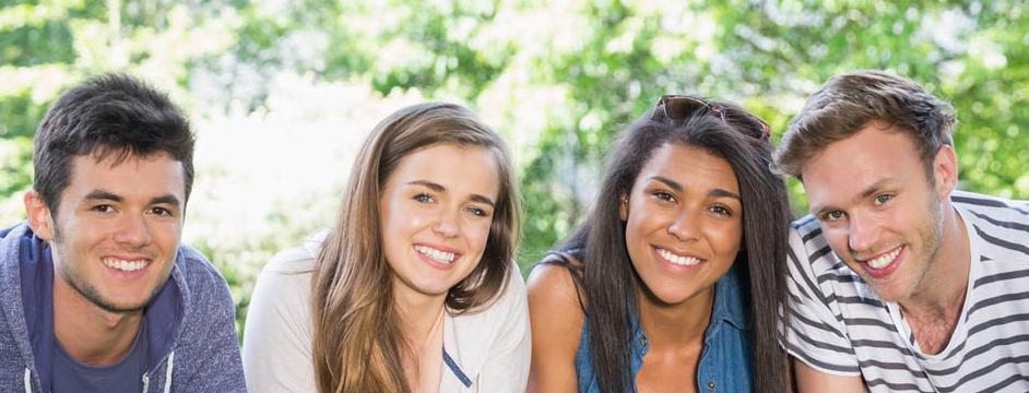 2 boys and 2 girls leaning on the grass smiling