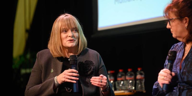 Close of two women, seated, looking at each other; one is speaking into a microphone Close of two women, seated, looking at each other; one is speaking into a microphone