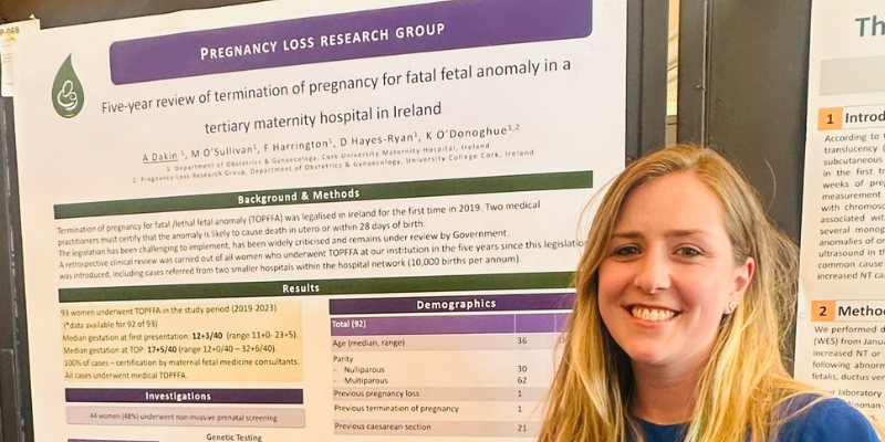 Woman standing beside a scientific poster at a conference