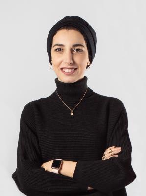 Female student, wearing a black turtle neck jumper and a black headscarf, posing for the camera smiling broadly with her arms folded. Female student, wearing a black turtle neck jumper and a black headscarf, posing for the camera smiling broadly with her arms folded.