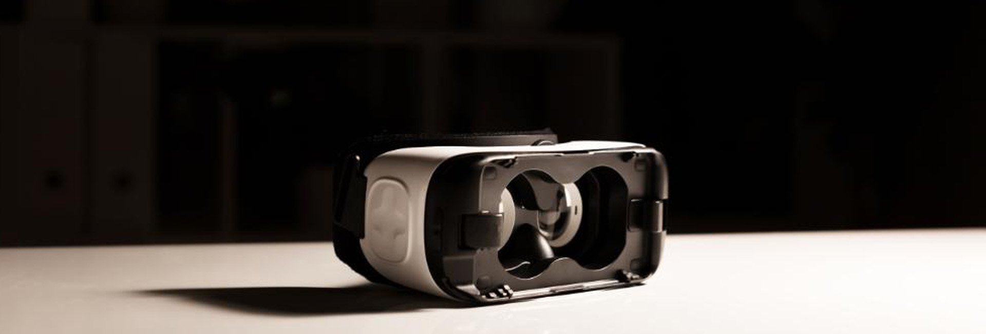black and white image of 3d goggles on a white tabletop with light coming from the right and casting a long shadow